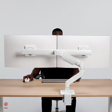 Individual sitting on eFloat Quattro desk, with M8 Pro Dual Screen Monitor Arm